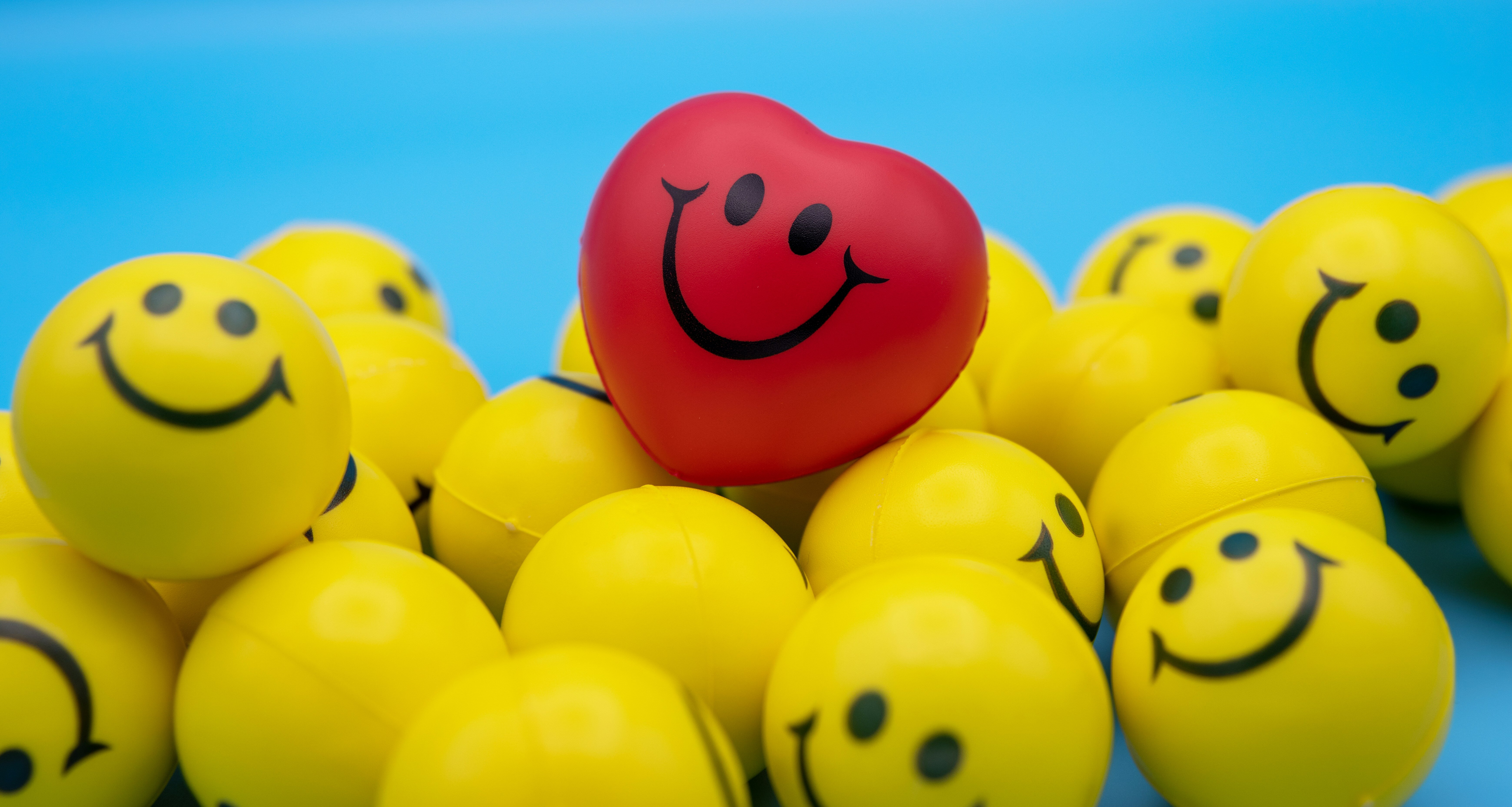 One heart smiling emoji sitting on a pile of yellow smiley face balls