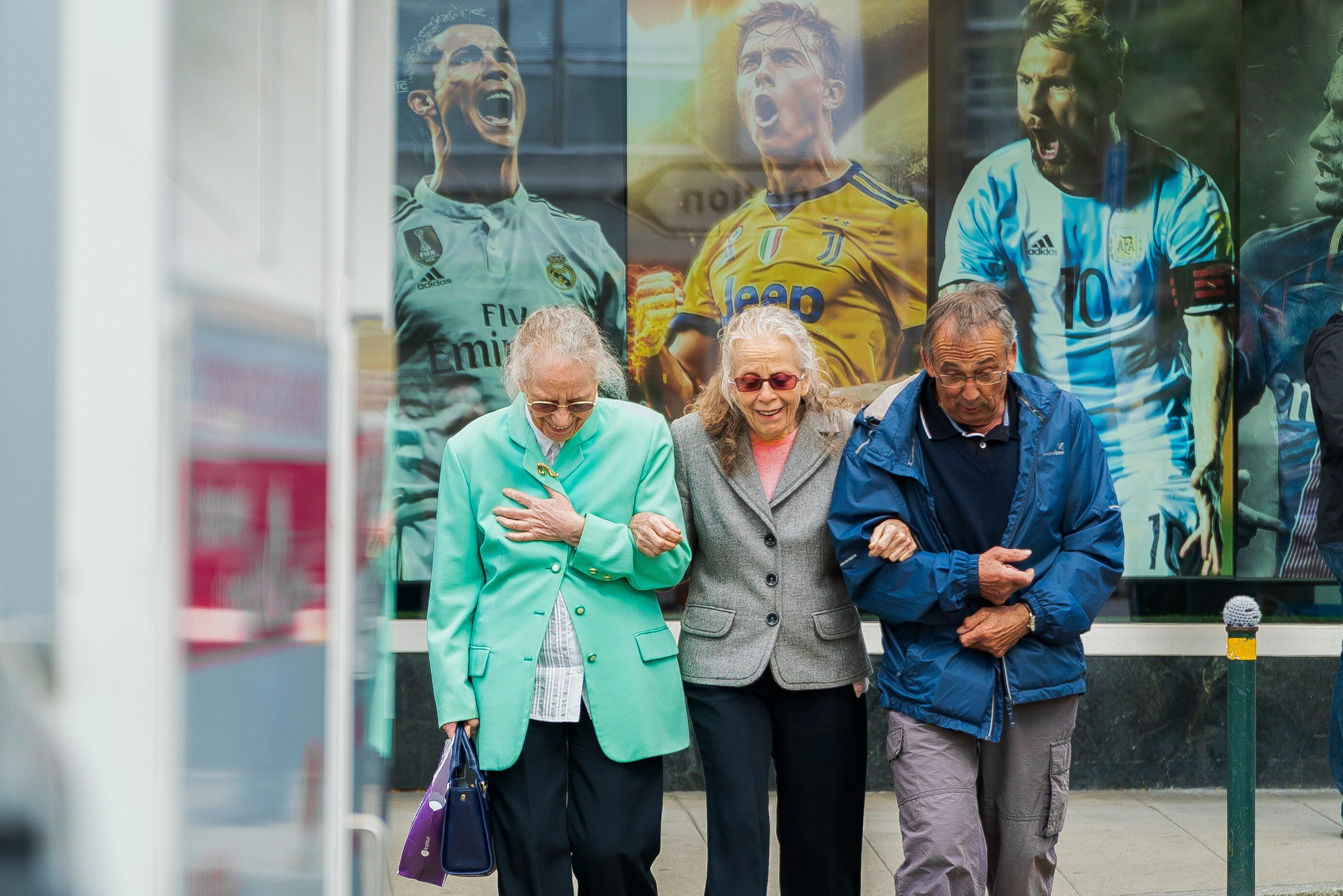 A trio of three older people walking arm-in-arm