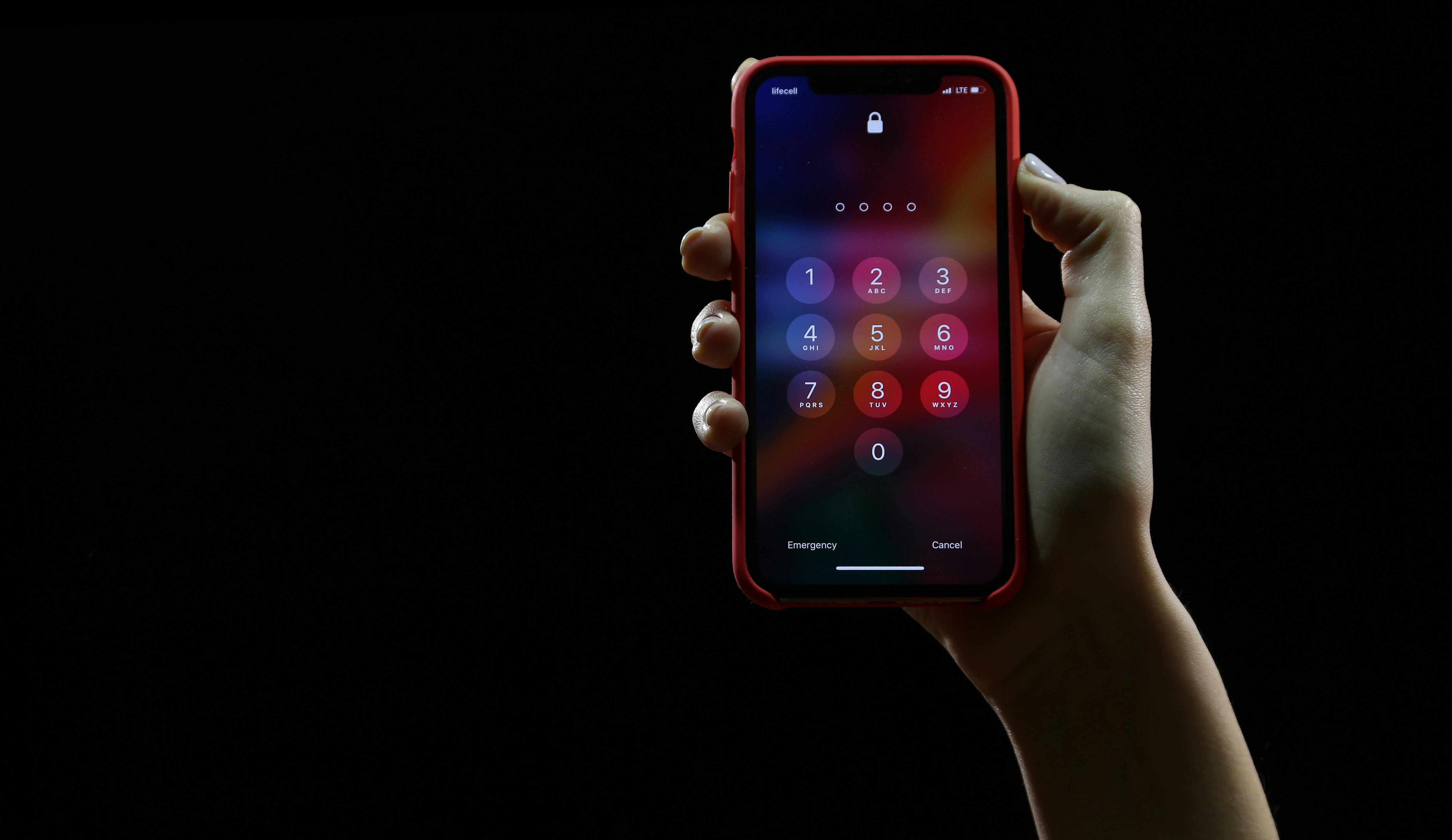 A black background with a hand holding up an iPhone showing the passcode screen on the right side.